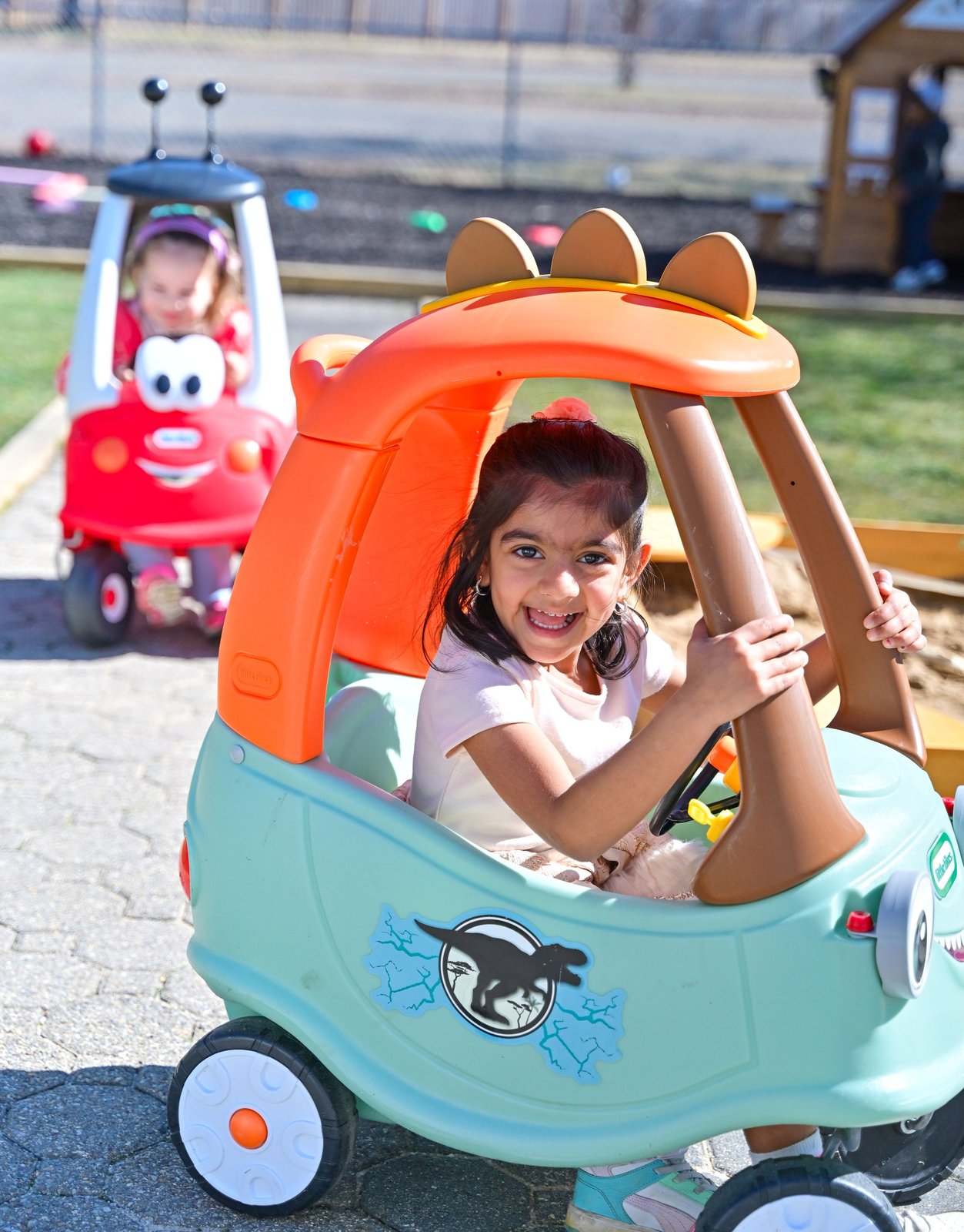 Smiling child in outdoor toy car at Milestones Montessori summer camp