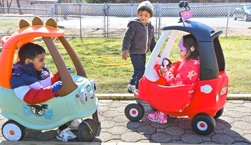 Children playing outdoors with ride-on toys at Milestones Montessori