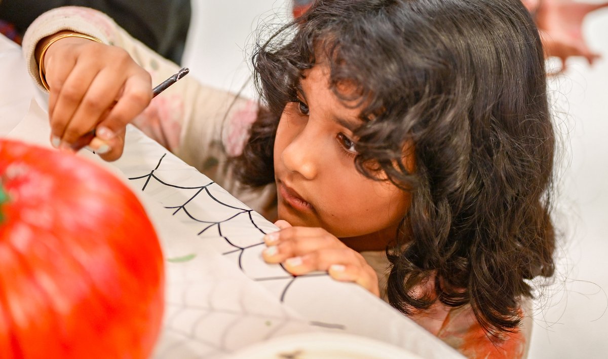 Child carefully painting a Halloween pumpkin in Montessori style