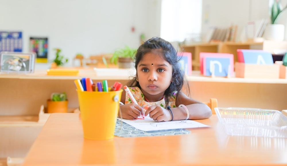 Child writing in Montessori work journal