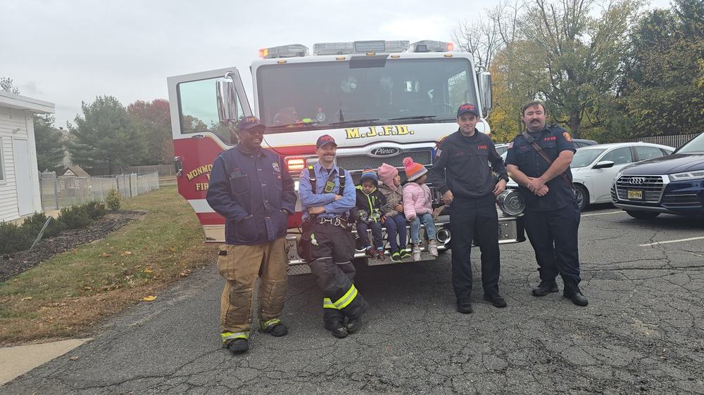 Children sitting with firefighters on a fire truck during a community visit