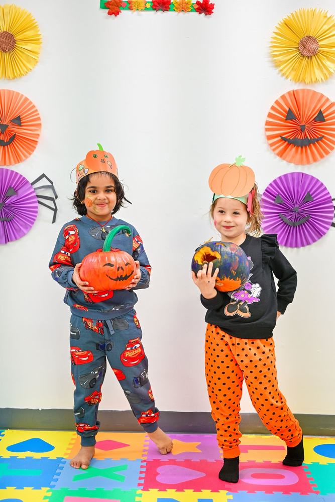 Two children in costumes holding the pumpkins they painted at last year's Milestones pumpkin event