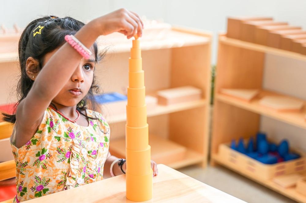 Child placing the smallest cube on top of the Montessori Pink Tower