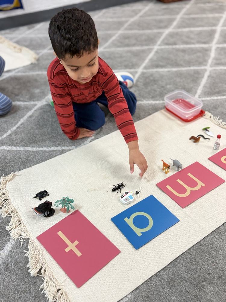 Child matching small objects to large letter cards by their beginning sounds