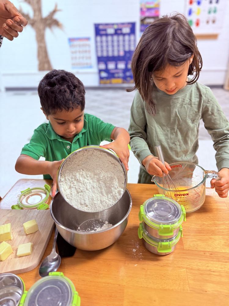 Two children sifting flour and mixing ingredients together in a baking activity